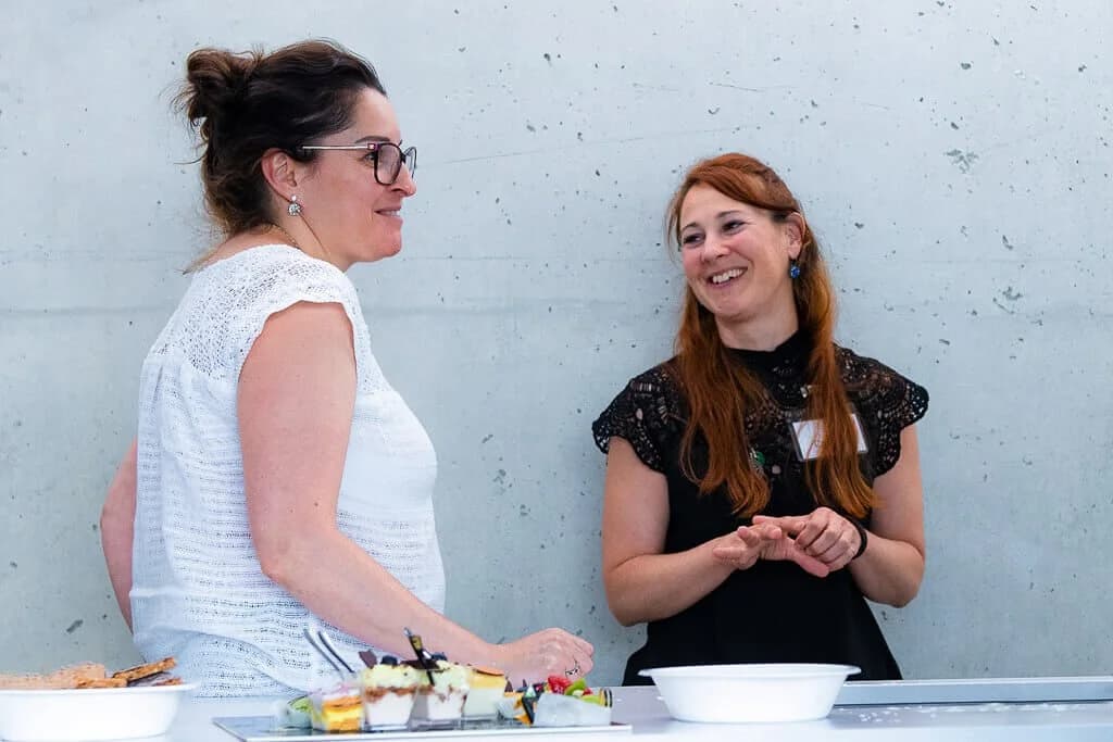 Deux participantes discutent près du buffet pendant une pause