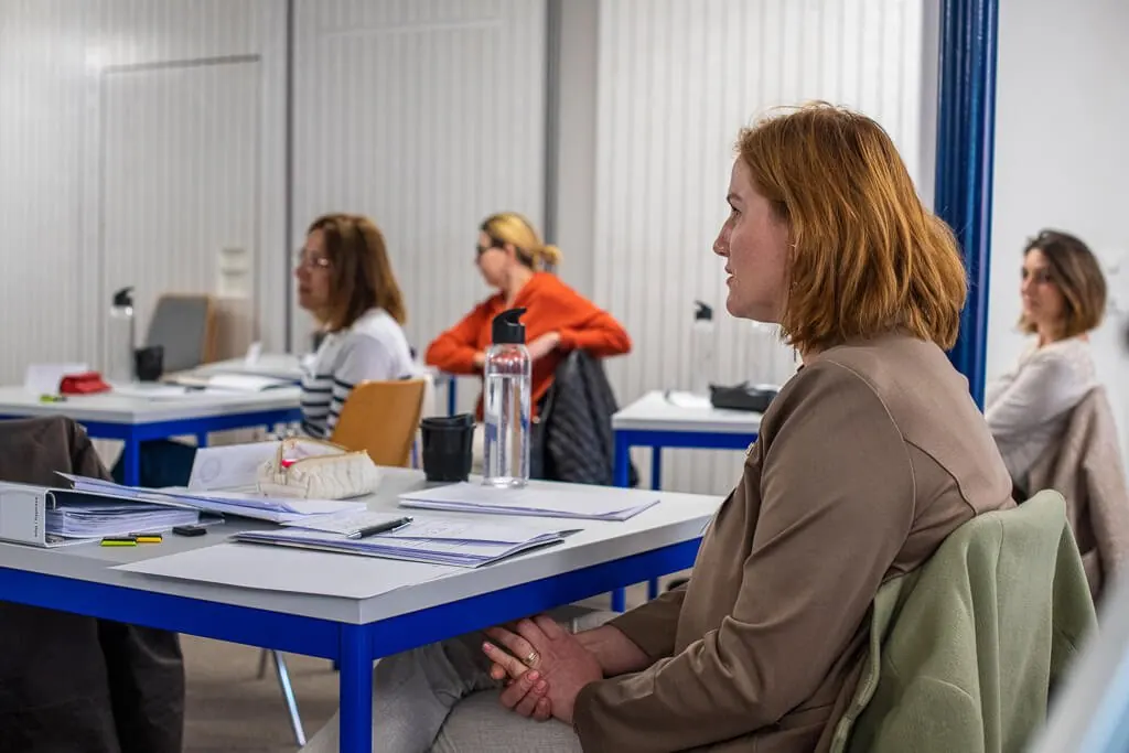 Des participantes écoutent depuis leurs tables pendant une formation