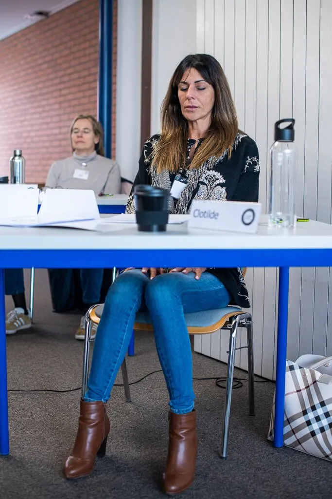 Une participante écoute, les yeux baissés, à sa table pendant un cours