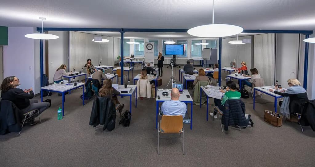 Vue d’ensemble d’une salle de formation, le groupe autour des tables